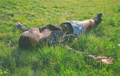Woman Lying On Green Grass With Stretched Arms And Legs By