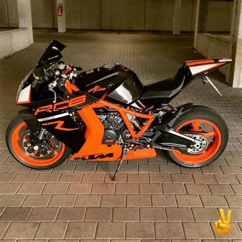 An Orange And Black Motorcycle Parked In A Parking Garage Next To A
