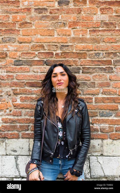 Portrait Of Young Woman Wearing Black Leather Jacket Brick Wall Stock