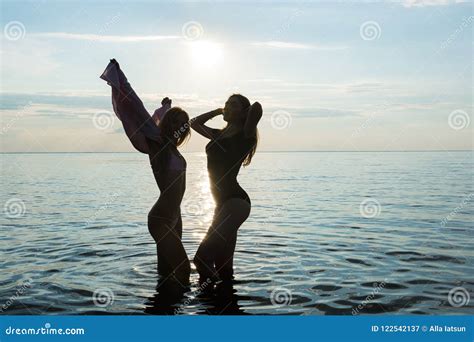 Two Beautiful Girls Are Dancing On The Beach At Sunset Sea Background Silhouettes Stock Image