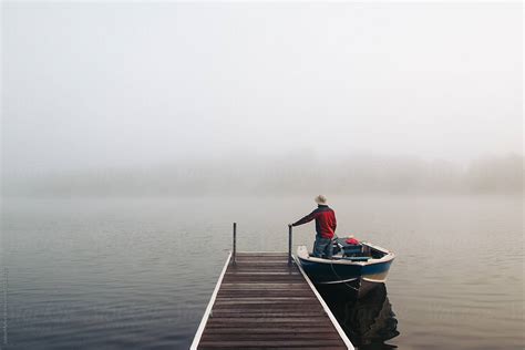 Man Standing With Boat Near A Dock On Foggy Lake By Stocksy Contributor Justin Mullet Stocksy