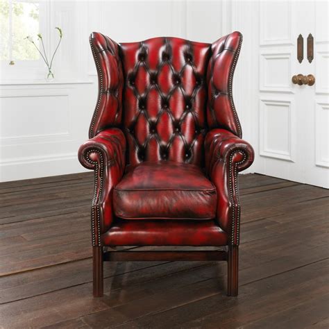 The seat is very soft and cushy on this vintage furniture from europe. red leather wingback chair with wooden floor and white ...