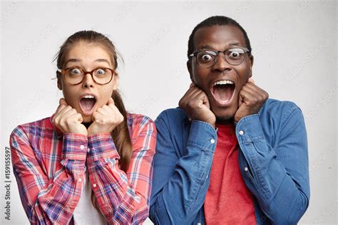 Excited Surprised Young Interracial Couple Dressed In Identical Clothes