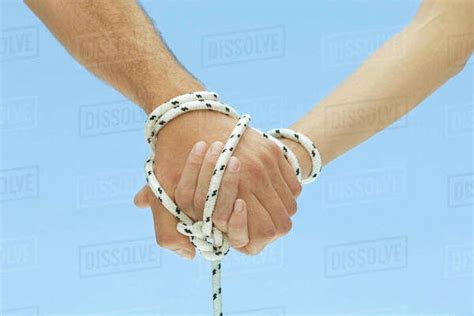 Man And Woman Holding Hands Tied Together With Rope Cropped View