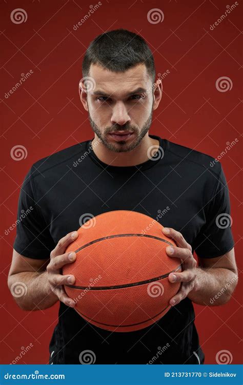 Seriously Basketball Player Holding With Both Hands A Orange Ball Stock