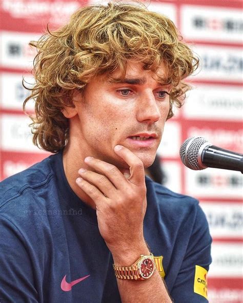 A Man With Curly Hair Sitting In Front Of A Microphone
