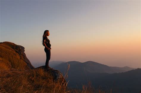 Free Photo Woman Standing On A Mountain Looking At Sunset