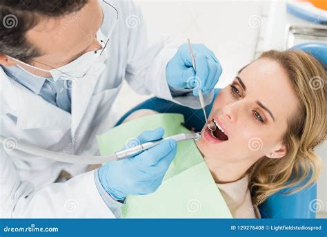 Female Patient At Dental Procedure Using Dental Drill In Modern Stock