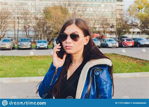 Cute Young Student Girl In Glasses Talking On Mobile Phone In Park