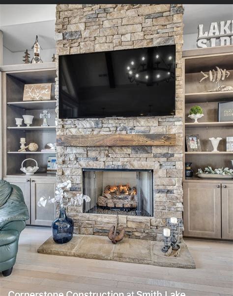 A Living Room With A Stone Fireplace And Entertainment Center