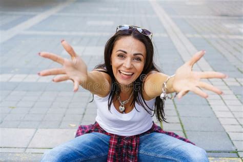 Happy Girl In White T Shirt Blue Jeans And White Sneakers Sits On