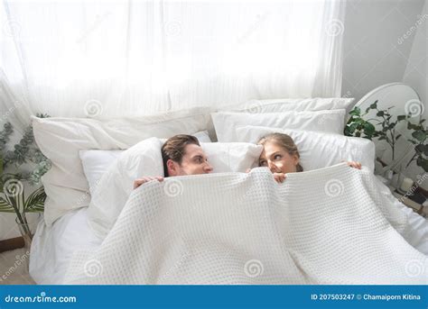 Cheerful Excited Caucasian Married Couple Lying In Bed Hiding Bodies Under White Blanket Stock