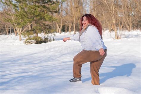 A Fat Red Haired Woman In A White Sweatshirt Walks Through Snowdrifts