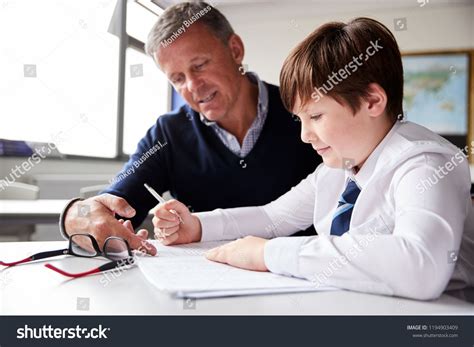 High School Tutor Giving Male Student Wearing Uniform One To One