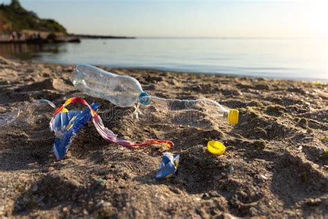 Polluted Beach With Plastic Garbage Lying On Sand Near Water Stock