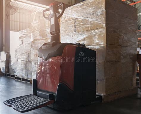 Cardboard Boxes On Wooden Pallet With Worker Driving Electric Forklift Pallet Jack Unloading At
