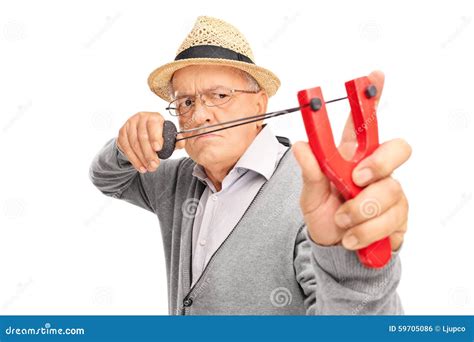 Angry Senior Aiming To Shoot A Rock With A Slingshot Stock Photo