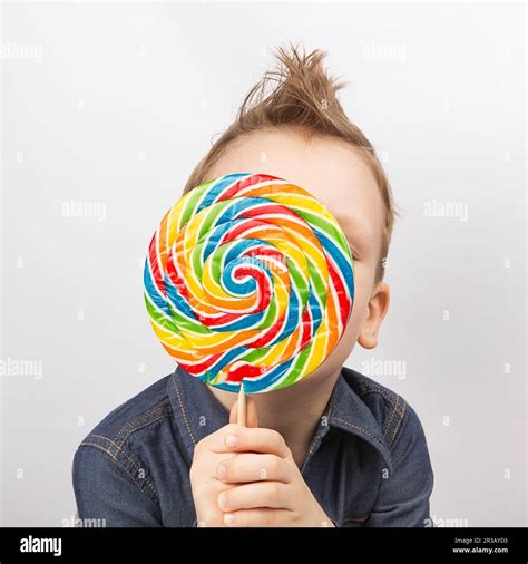 A Boy In A Denim Shirt Eating Lollipop Happy Kid With A Big Candy