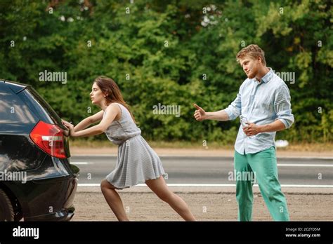 Young Couple Pushing Broken Car On Road Breakdown Crashed Automobile