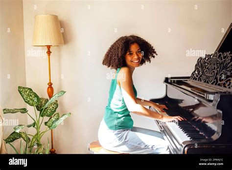 Young black lady playing a piano. Happy smiling woman enjoy fun