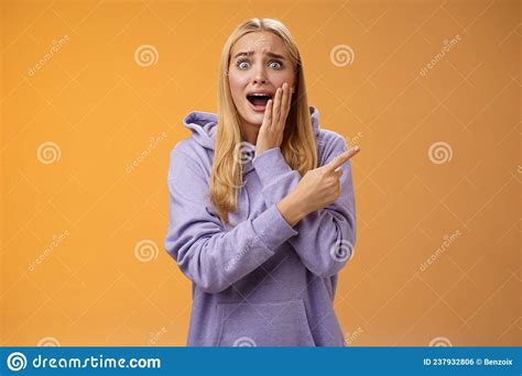 Amazed Excited Overwhelmed Young Blond Girl In Hoodie Press Palm Cheek