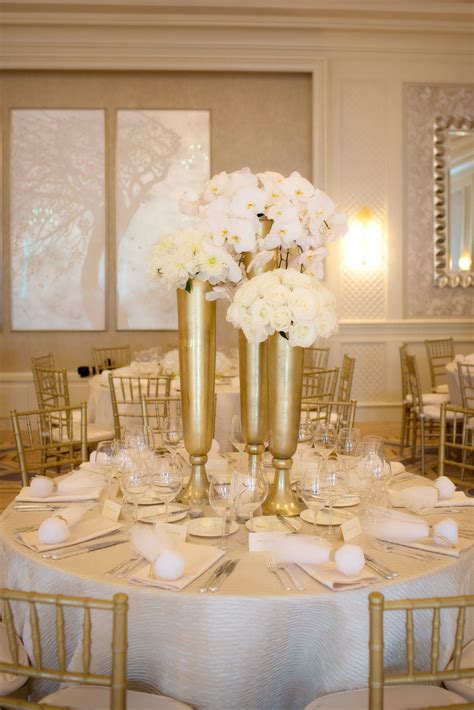 White Floral Centerpieces In Tall Gold Vases