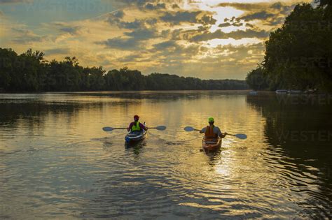 Couple Kayaking In River At Sunset Stock Photo