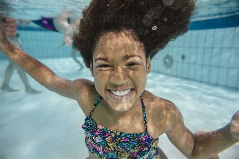 Portrait Of Smiling Girl Under Water In Swimming Pool Stock Photo