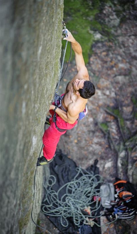 Muscular Rock Climber Climbs On Cliff Wall With Rope Stock Photo