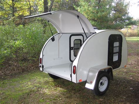 An Enclosed Camper Trailer Parked In The Woods With Its Door Open To
