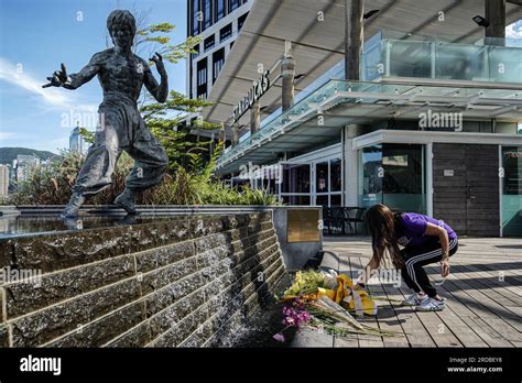 A woman puts down a brunch of flowers in front of the statue of Bruce