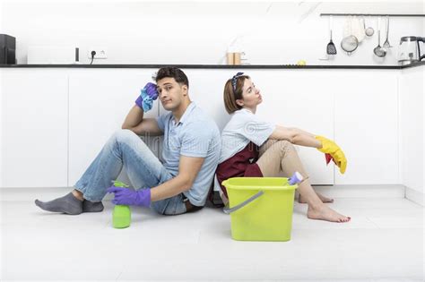 Tired Couple Sitting On The Floor After Exhausted Cleaning Day At Home