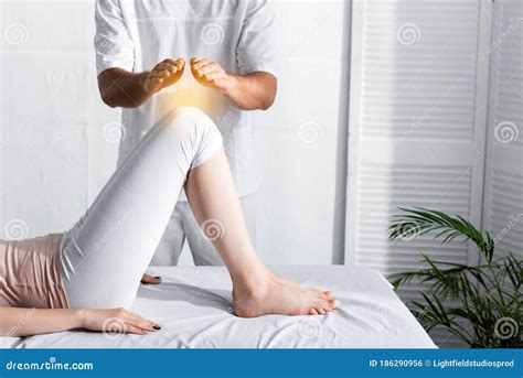 View Of Healer Standing Near Woman On Massage Table And Holding Hands