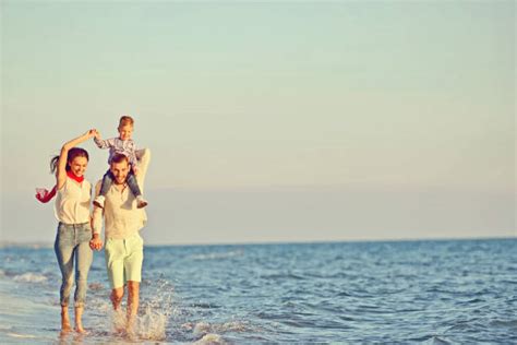 Madre Con Dos Hijos Caminando En La Playa Al Atardecer Banco De Fotos