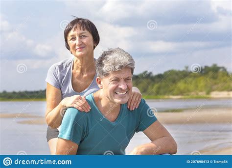 Mature Woman Hugs A Man From Behind On The Beach Stock Image Image Of