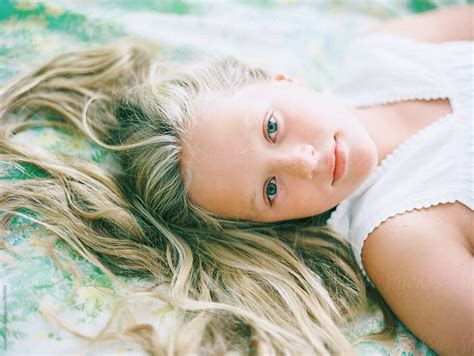 Portrait Of Blonde Girl Wtih Hair Spread Out On Vintage Floral Sheets By Stocksy Contributor