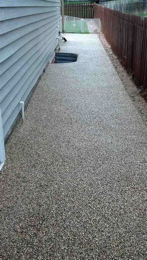 A Driveway With Gravel On The Side Of It And A Fence In The Back Ground