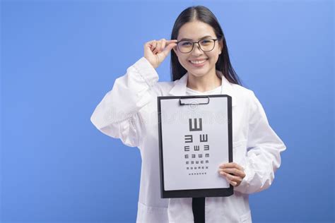 Young Female Ophthalmologist With Glasses Holding Eye Chart Over Blue