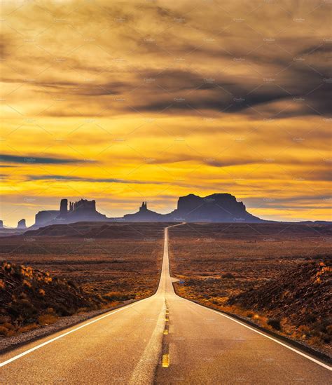 Desert Road Leading To Monument Valley At Sunset Featuring Monument