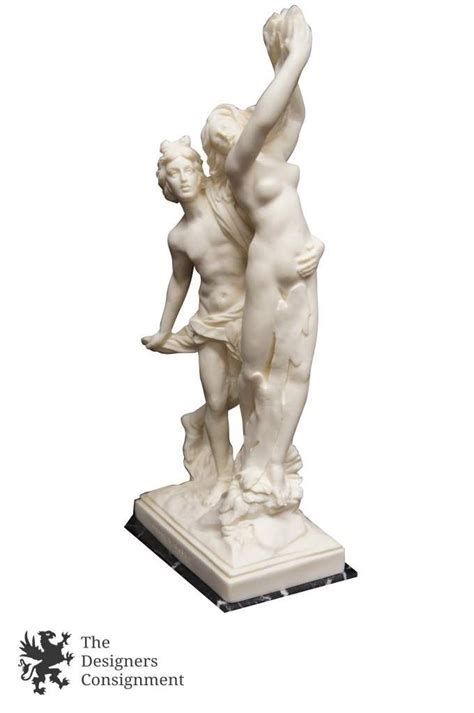A White Statue With Two People Holding Each Other S Arms In Front Of A