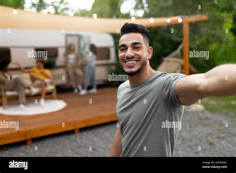 Happy Arab Guy Taking Selfie Near Motorhome Resting On Campsite With Multiracial Friends