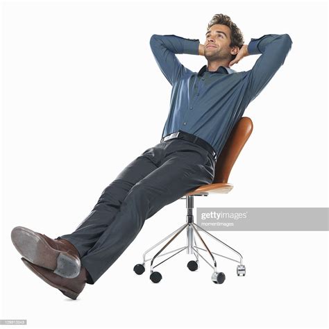 Studio Shot Of Young Business Man Relaxing On Chair With Hands Behind