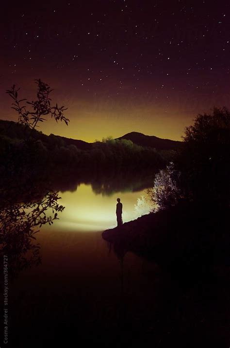 Man Standing On Lake Edge At Night On Surreal Landscape