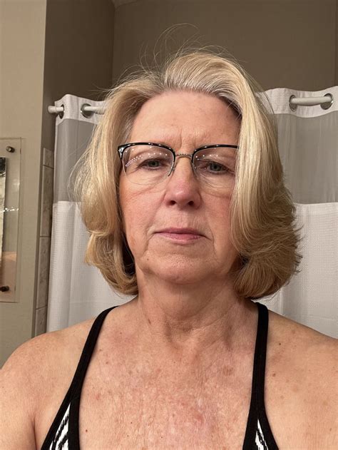 an older woman with glasses is looking at the camera in front of a bathroom mirror