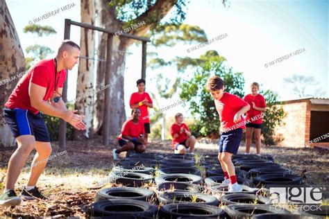 Trainer Instructing Kids During Tyres Obstacle Course Training Stock