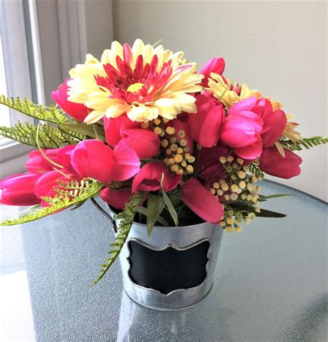 A Vase Filled With Pink And Yellow Flowers On Top Of A Table Next To A