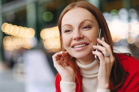 Headshot Of Smiling Female Employee With Cheerful Facial Expression Uses Smart Phone Gadget For