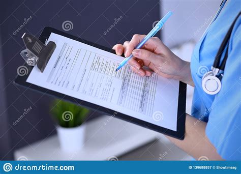 Female Doctor Filling Up Medical Form On A Clipboard Closeup