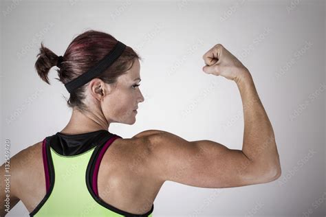 beautiful strong muscular woman flexing her biceps and arm muscles view from behind to show her