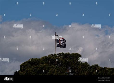 The Jolly Roger Pirate Flag Flies Proudly Against The Clouds Stock